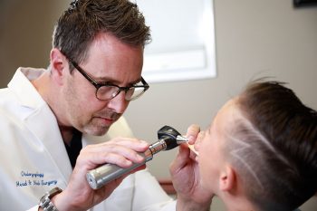 Adam S. Morgan, MD examines a patient's tonsils.
