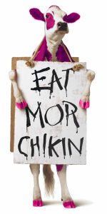 A cow with pink spots holding a Chick-fil-A "Eat More Chicken" sign