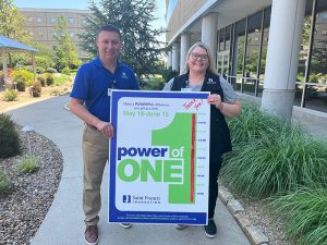 Stacy Huff and Rebecca Rose hold a Power of One tote board.