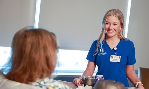 A nurse serves a patient her meal