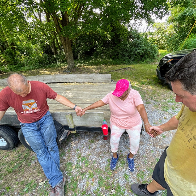 Foundation colleagues Jimmy Wilferth and Stacy Huff pray with Rae Shaw-Johnson