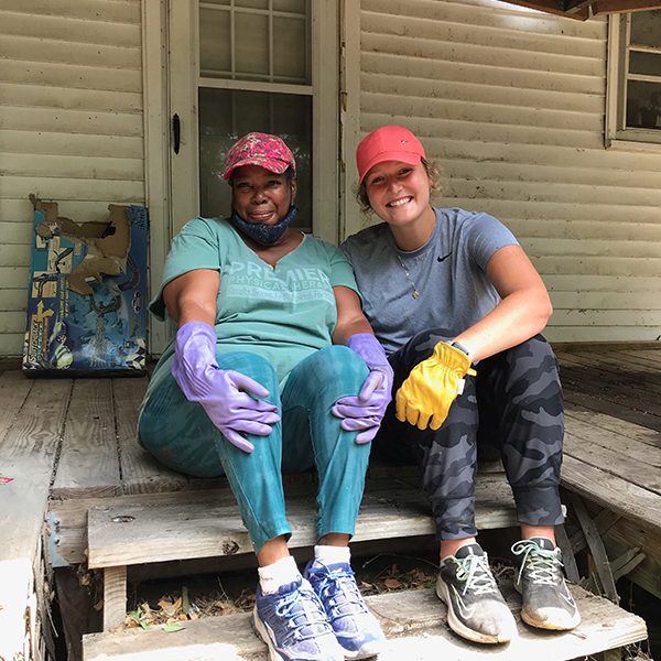 Rae Shaw-Johnson and volunteer Chrissy Wilferth pause working to pose on Johnson's porch