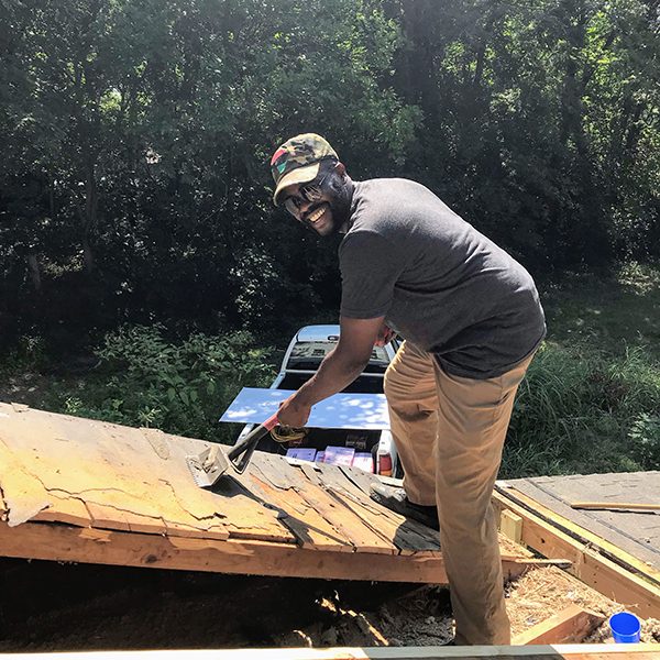 Saint Francis colleague Wyky Jean removes old shingles from the roof