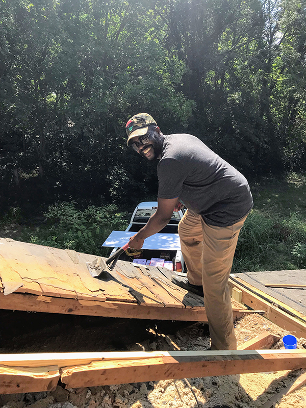 Saint Francis colleague Wyky Jean removes old shingles from the roof