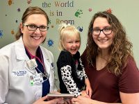 Julie A. Benard, MD, FAAP, DABOM, pediatrician with Cape Physician Associates, shares a book and a smile with Kirstan Mirgeaux and her daughter, Annie