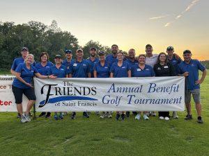 Members of the Friends of Saint Francis pose with a banner at the 2023 Friends of Saint Francis Golf Tournament