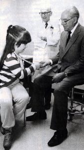 Roy Ritchie, former Physical Therapist at Saint Francis and Thomas Otto, MD, former Orthopedic Surgeon at Saint Francis, visit with a young polio patient.