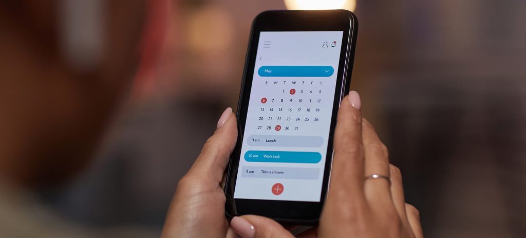 Close-up of woman using online calendar on mobile phone to plan her week